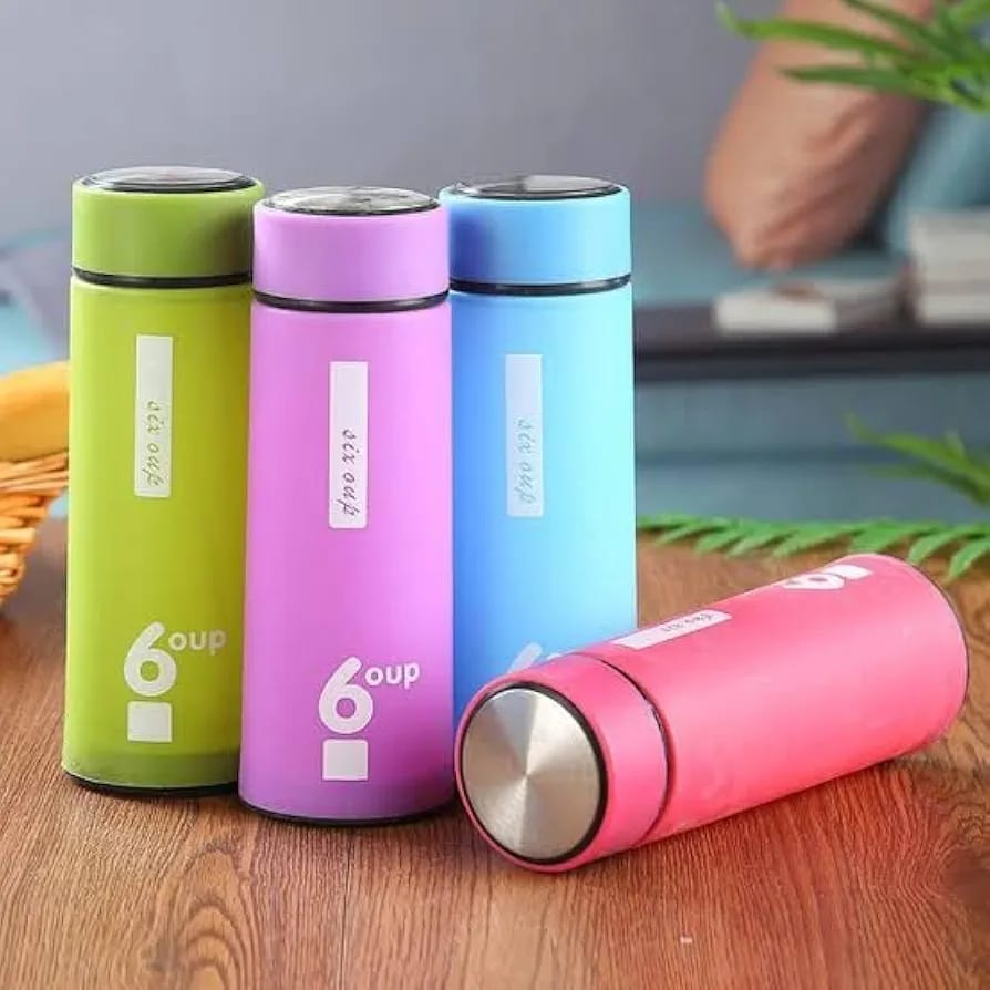 Four insulated 6-ounce travel mugs in green, purple, blue, and pink, displayed on a wooden tabletop with a softly blurred indoor background.